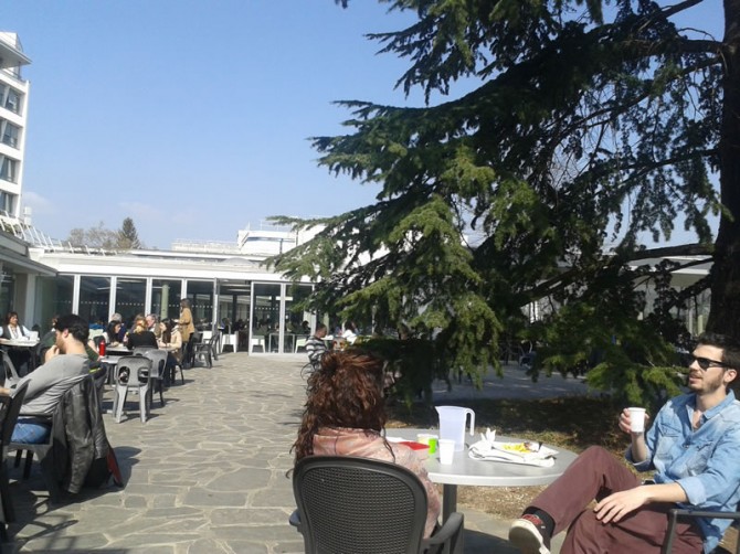 Cafeteria CERNA – u prednjem planu dvoje mladih znanstvenika tik prije nego će im na um pasti ideje njihovih znanstvenih karijera…